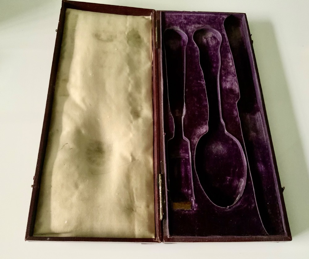 A three-piece Georgian silver cutlery set in the Coburg pattern, presented inside a velvet-lined display case. View IV