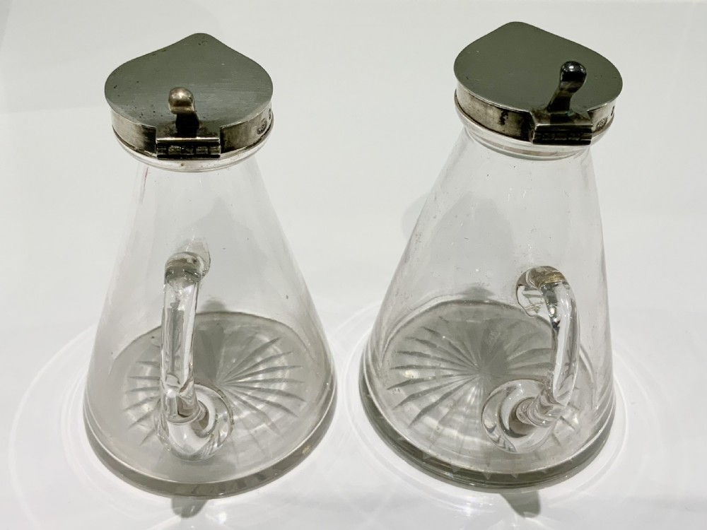 A pair of conical clear glass whisky noggins with star-cut bases and hallmarked sterling silver hinged lids. View II