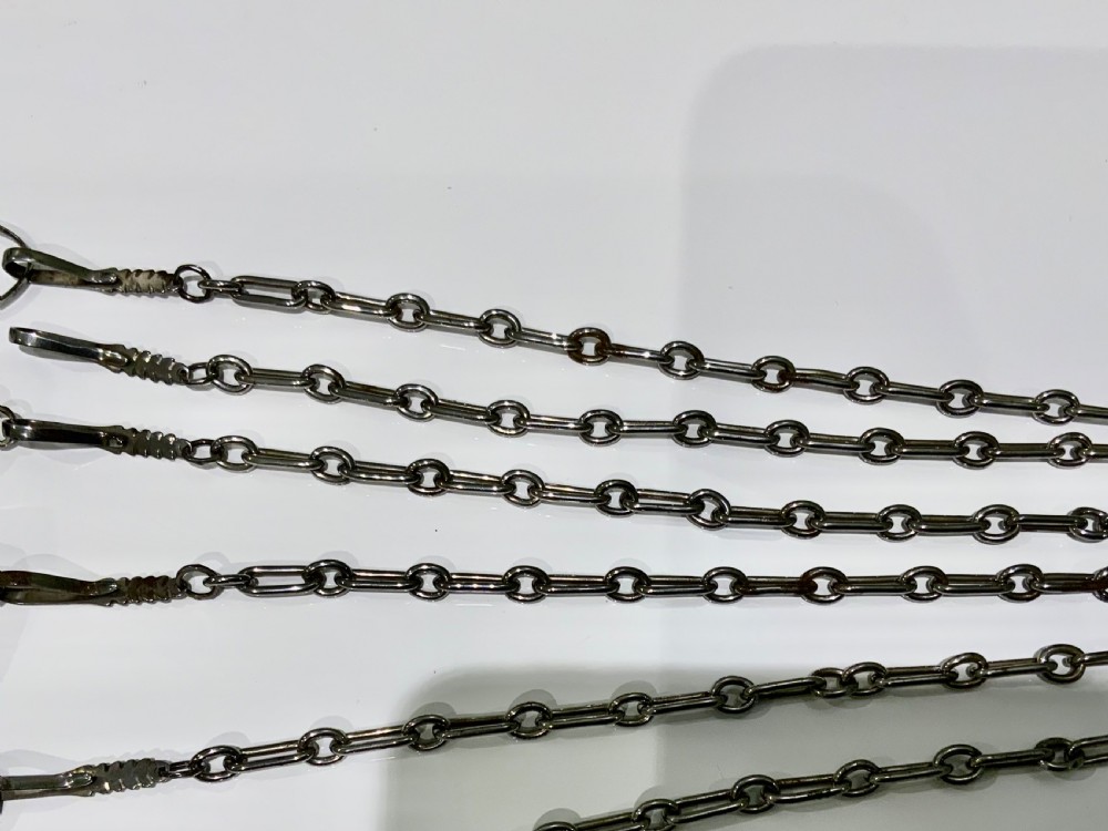 A nineteenth-century steel chatelaine featuring an ornamental waist clip and five suspended chains holding sewing tools, a key, a thimble, and a tape measure. View II