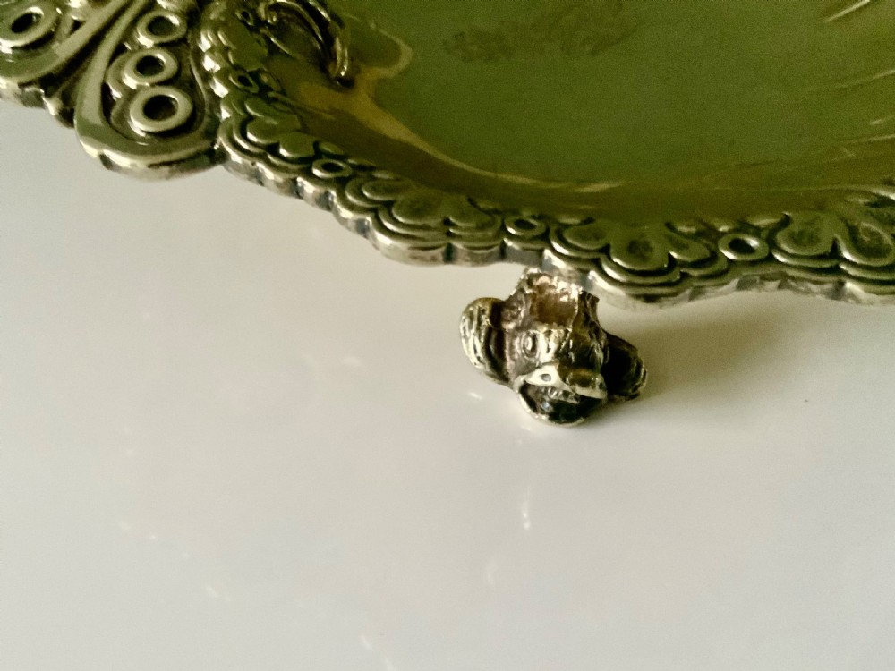 A Victorian shell-shaped silver-gilt dish with lobed fluting, a scalloped scroll rim, and an engraved crest at the centre. View V