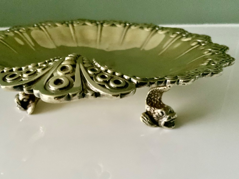 A Victorian shell-shaped silver-gilt dish with lobed fluting, a scalloped scroll rim, and an engraved crest at the centre. View VI