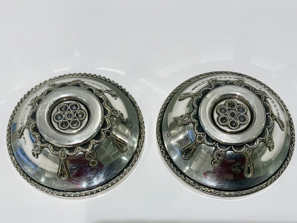 A pair of circular silver travelling candlesticks with flared nozzles and decorative beaded and teardrop filigree motifs along the conical bases. View IV
