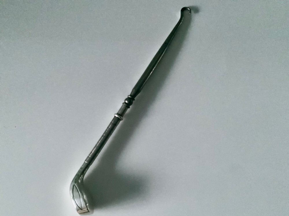 A sterling silver button hook featuring a handle shaped like a golf club head with a textured grip.