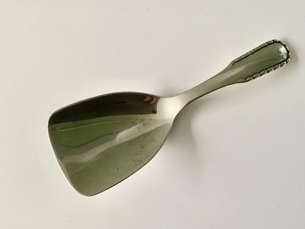 A sterling silver caddy spoon with a wide shovel-shaped bowl and a tapered handle featuring beaded relief edging.