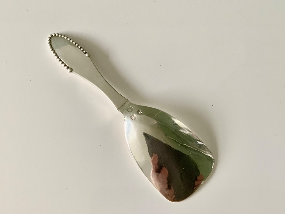 A sterling silver caddy spoon featuring a wide shovel-shaped bowl and a tapered handle trimmed with beaded detailing. View III