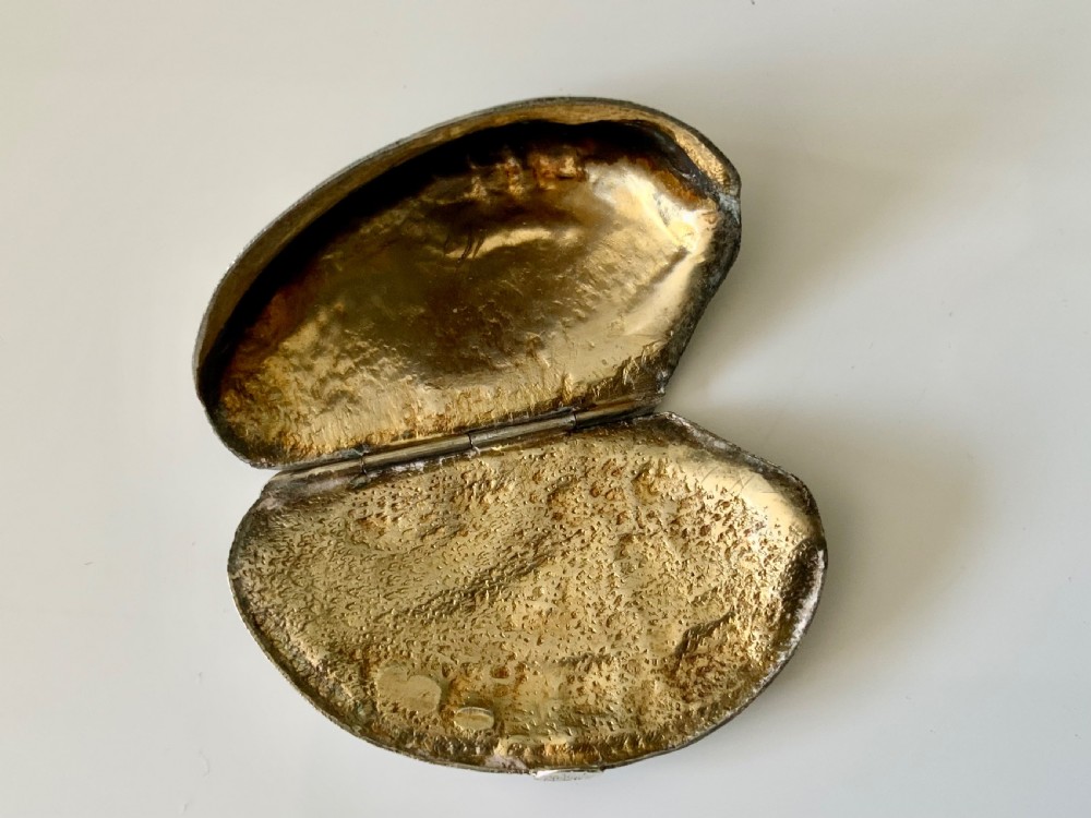 An angled view of a sterling silver vesta box cast in the realistic textured shape of a Brazil nut. View IV