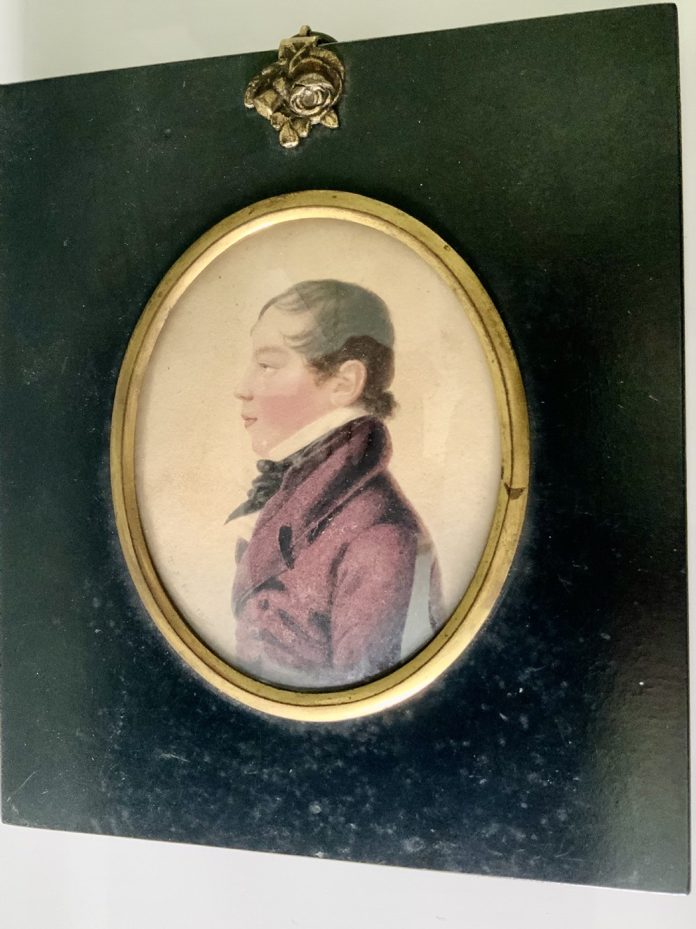 A pair of early nineteenth-century watercolour portrait miniatures depicting a lady and a gentleman, mounted in oval brass bezels set within rectangular black ebonised frames with top hanging loops. View III