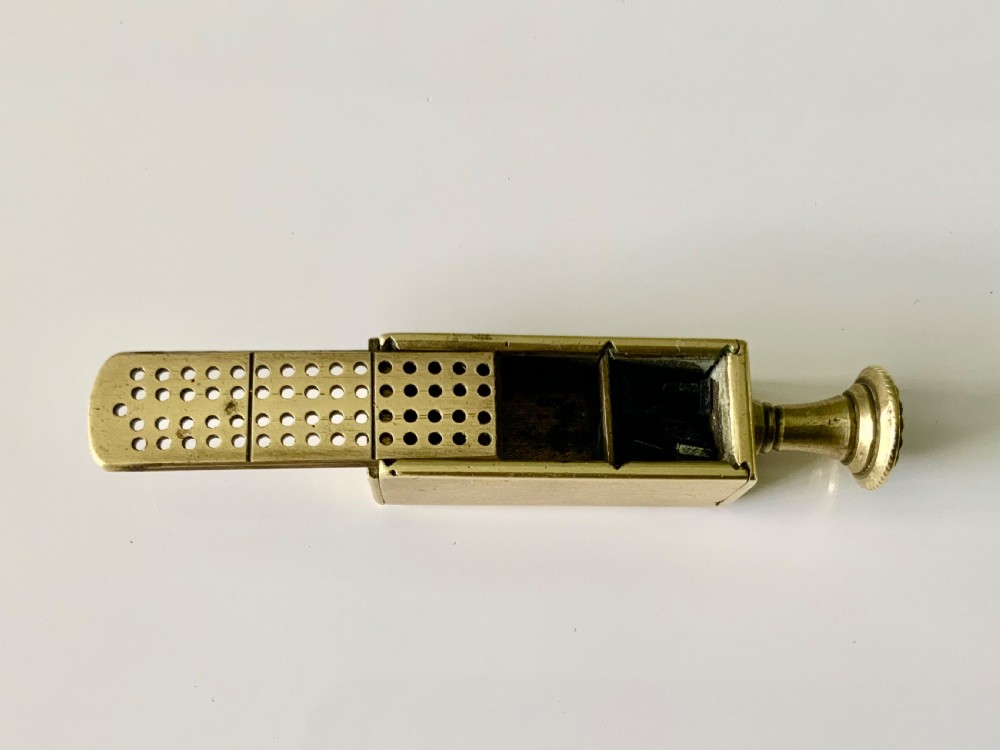 A nineteenth-century cast brass pipe tamper featuring a rectangular miniature cribbage scoring board connected to a turned pedestal handle. View II