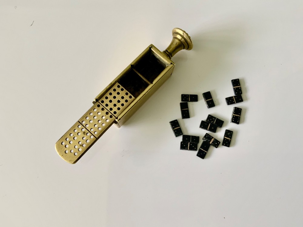A nineteenth-century cast brass pipe tamper featuring a rectangular miniature cribbage scoring board connected to a turned pedestal handle. View III