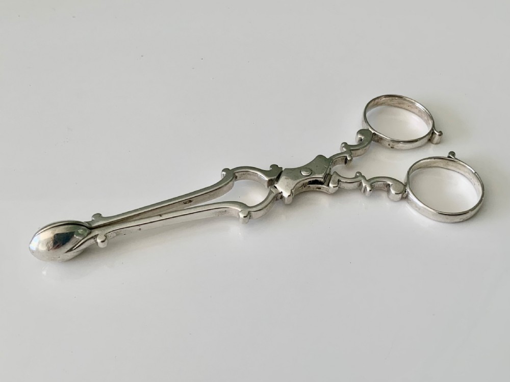 A pair of Georgian sterling silver scissor-action sugar nips with finger loops and shaped terminal grips.