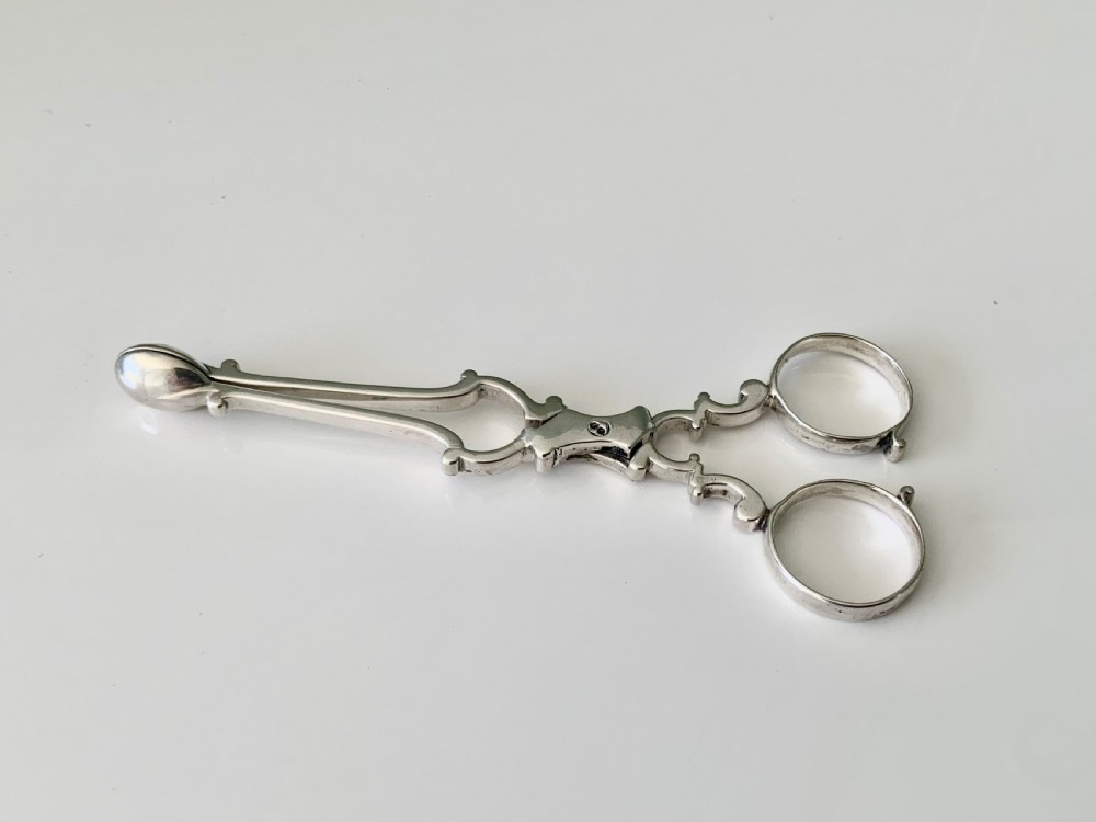 A pair of Georgian sterling silver scissor-action sugar nips with finger loops and shaped terminal grips. View II