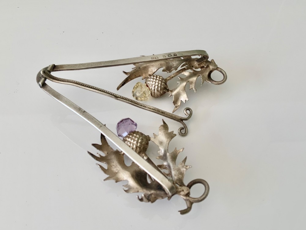 An easel-backed silver menu holder featuring detailed Scottish thistle leaves and two thistle heads set with faceted purple and yellow stones. View III