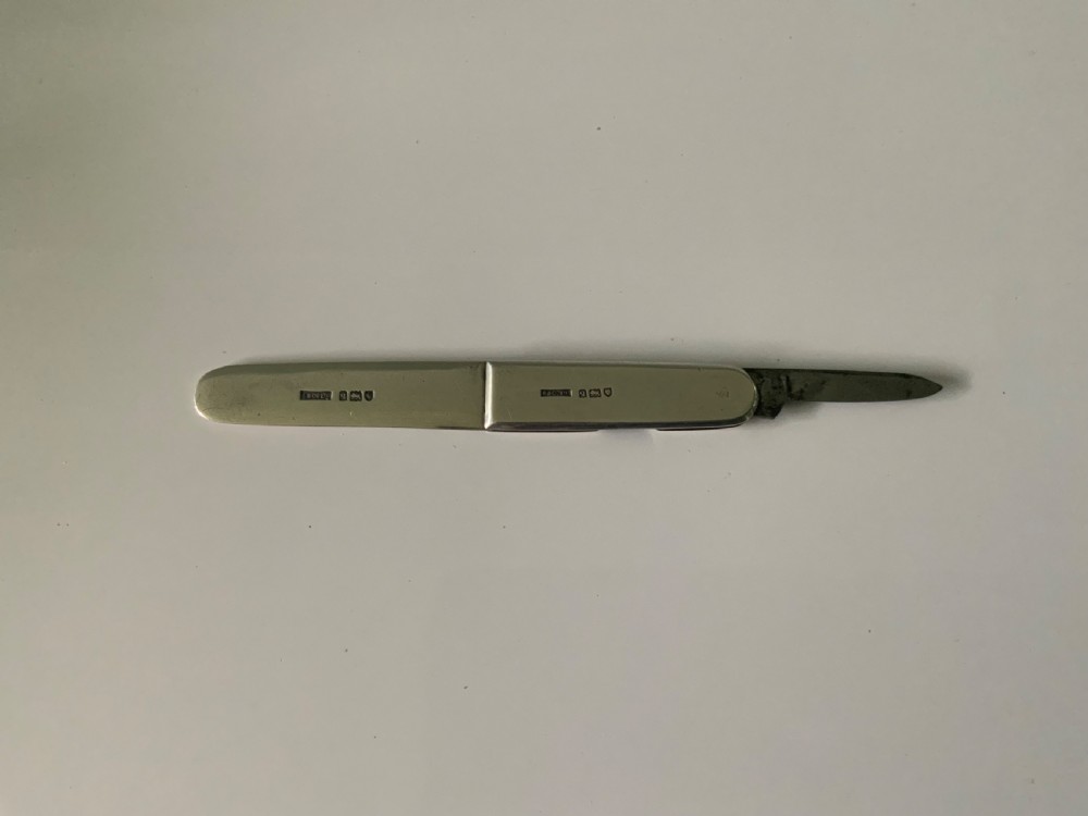 A sterling silver folding letter opener knife combination displaying hallmarked stamps along its casing.