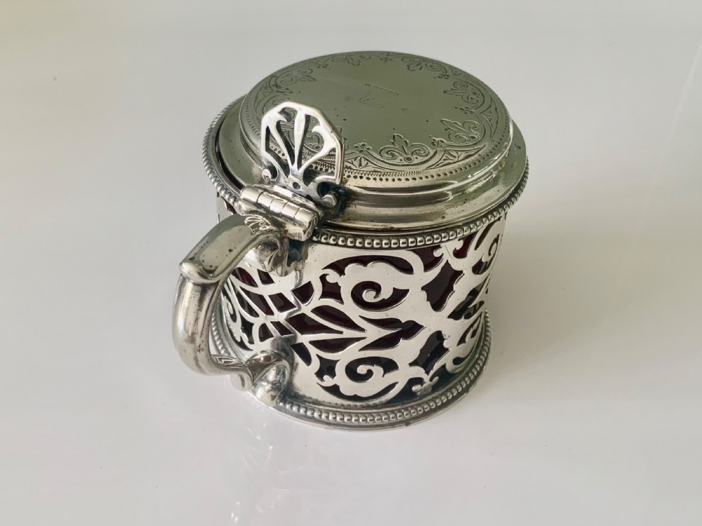 A pierced silver mustard pot with an engraved hinged lid, beaded rims, and a visible ruby red glass liner. View III
