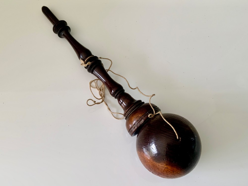 A lathe-turned dark wood bilboquet featuring a slender stem, attached cord, and a polished wooden sphere resting atop the spindle. View IV