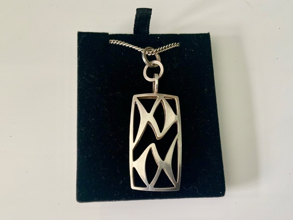 A rectangular sterling silver pendant featuring openwork geometric cut-outs suspended from a fine silver chain. View II