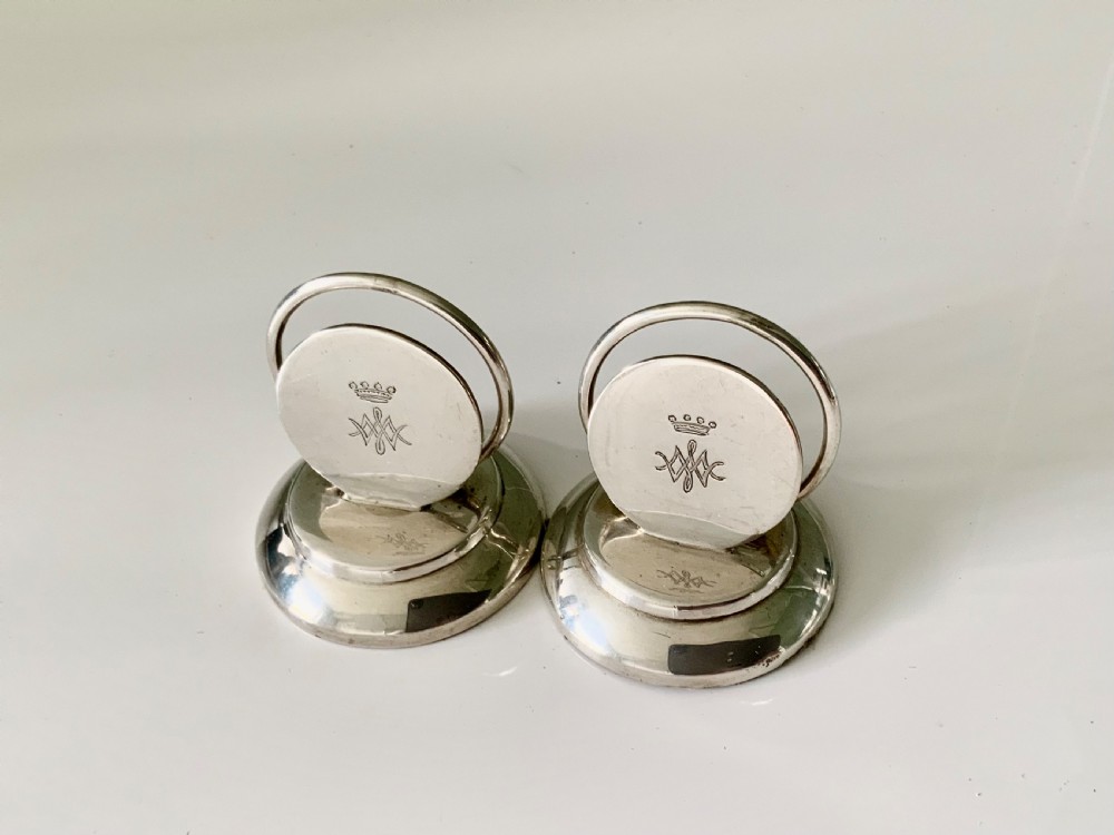 A pair of circular silver menu holders with stepped round bases and engraved coronet monograms.