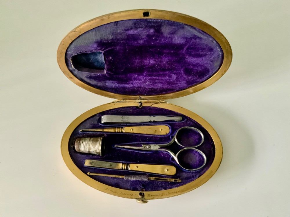 An oval brass Victorian sewing etui decorated with detailed floral engravings and a central monogrammed cartouche. View II