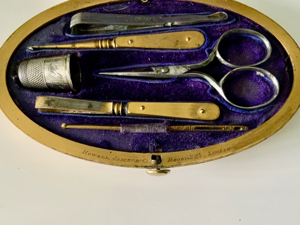 An oval brass Victorian sewing etui decorated with detailed floral engravings and a central monogrammed cartouche. View III