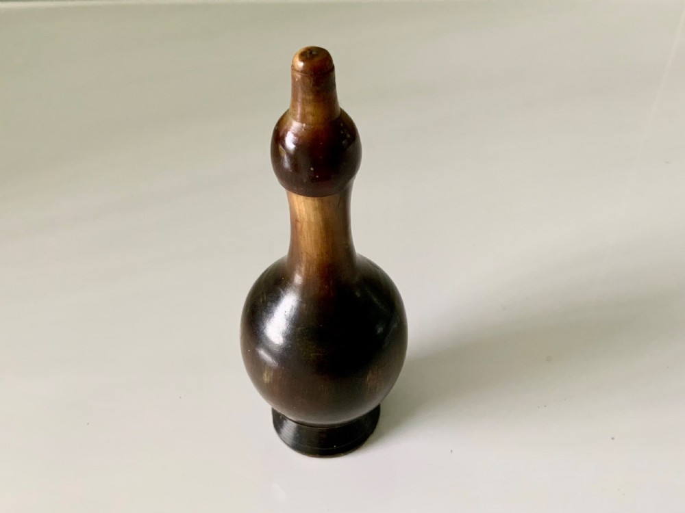 A 19th-century turned horn glove powderer featuring a rounded bulbous base, a narrow neck, and a polished dark brown finish.