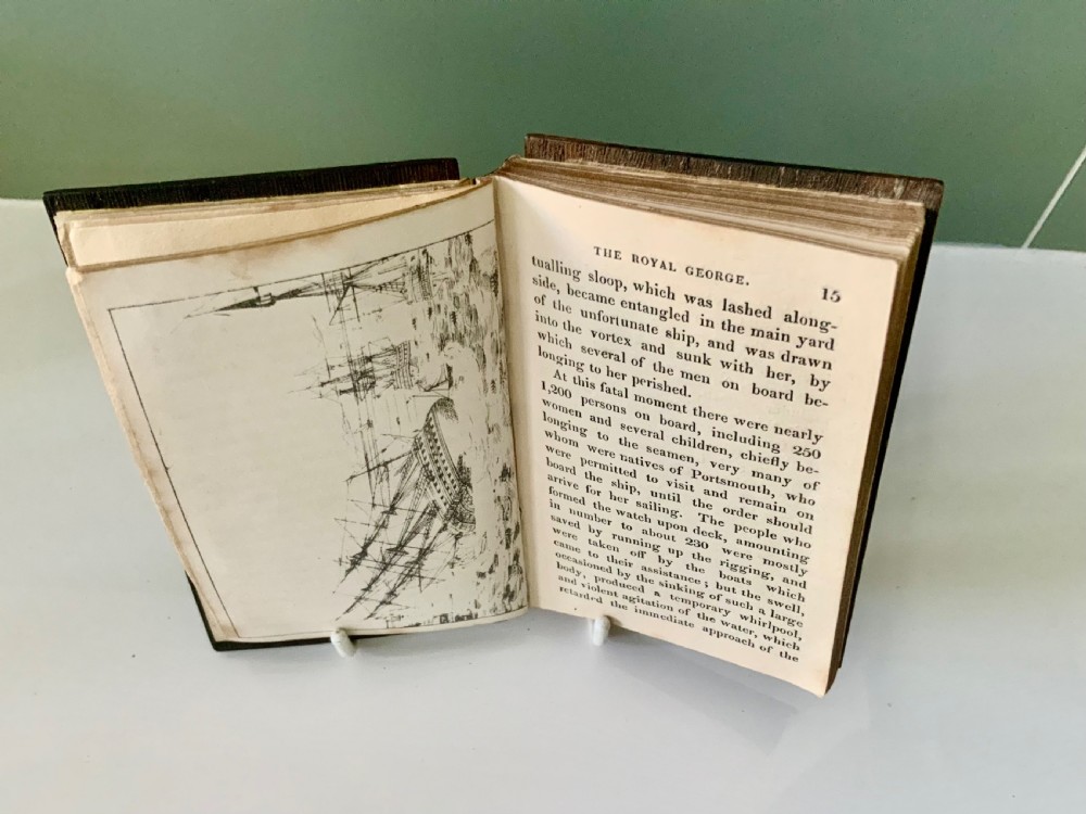 An open nineteenth-century book showing an engraved frontispiece illustration of a ship sinking on the left and a printed title page titled A Narrative of the Loss of the Royal George on the right. View V