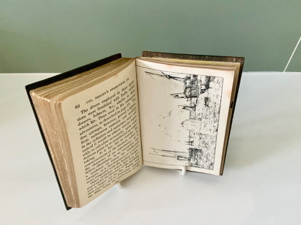An open nineteenth-century book showing an engraved frontispiece illustration of a ship sinking on the left and a printed title page titled A Narrative of the Loss of the Royal George on the right. View VI