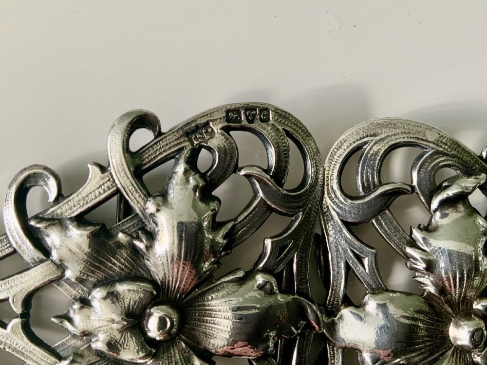 A two-piece sterling silver Art Nouveau belt buckle featuring floral openwork and sinuous curves mounted on a black band. View III