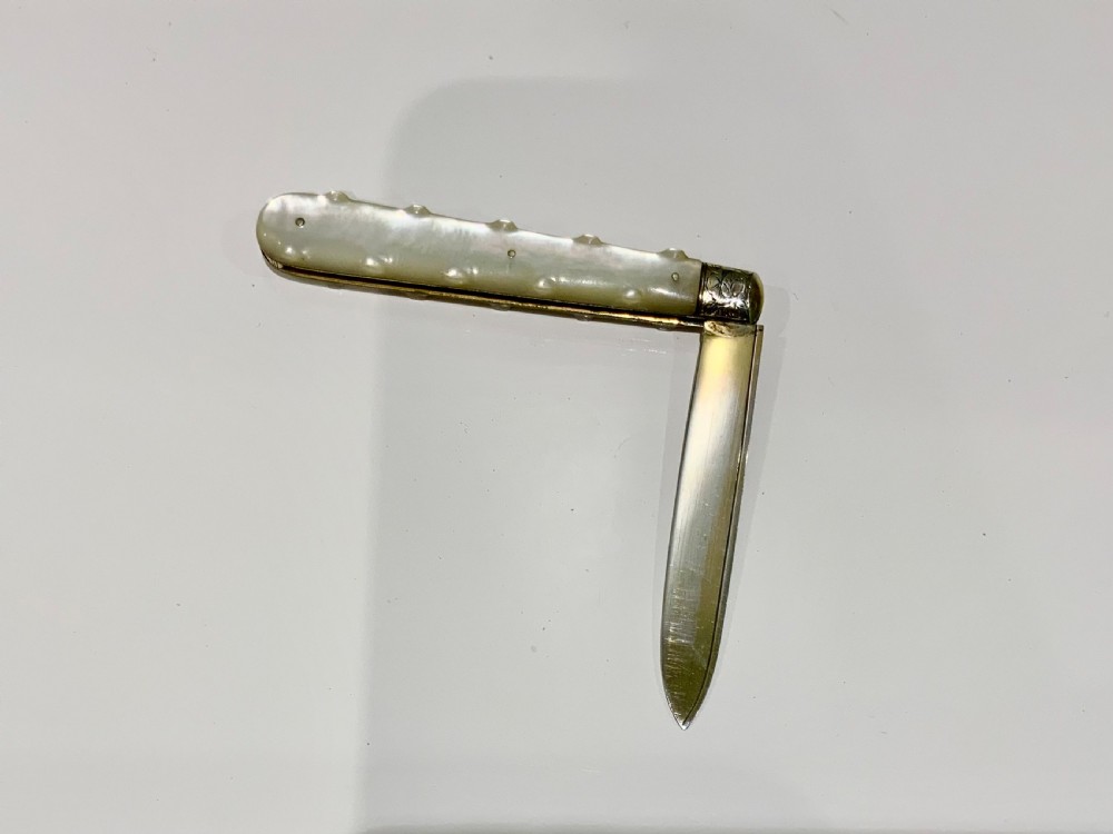 A Victorian folding fruit knife with an engraved sterling silver blade bearing official British hallmarks and a carved mother-of-pearl handle. View V