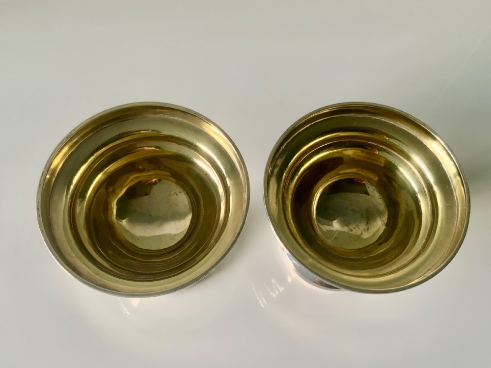 A pair of polished silver pedestal dishes featuring stepped circular bases and interior gold-gilded bowls. View V