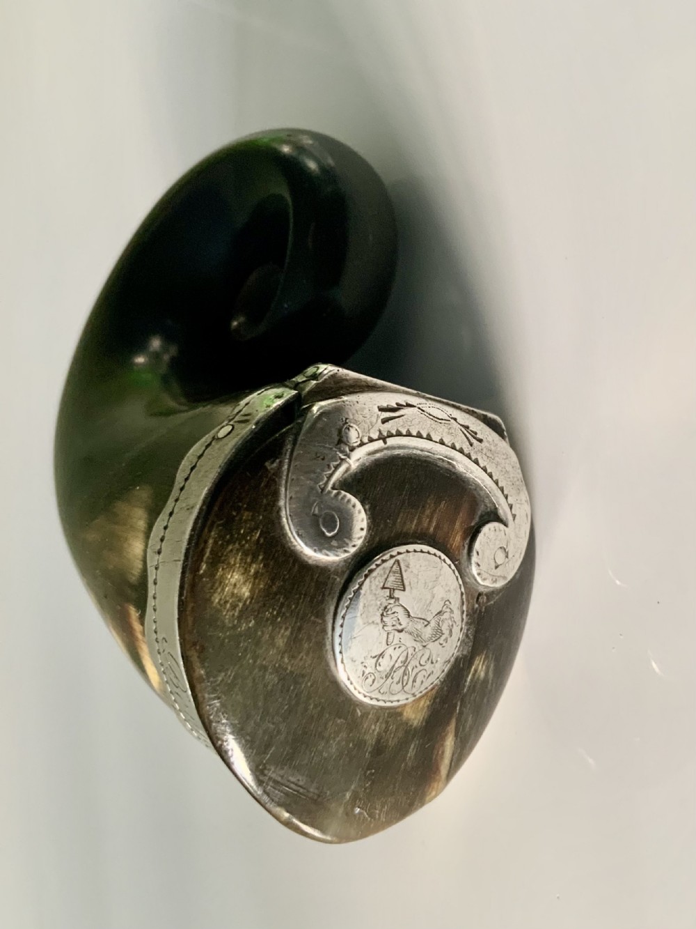 A nineteenth-century Scottish horn snuff mull featuring a curled natural horn body topped with engraved silver mounts and a hinged lid.