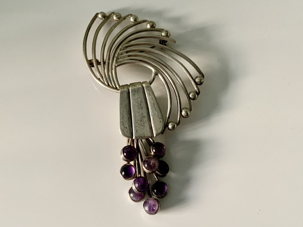 A Mexican sterling silver brooch designed with sweeping curved wires and hanging purple amethyst cabochons. View II