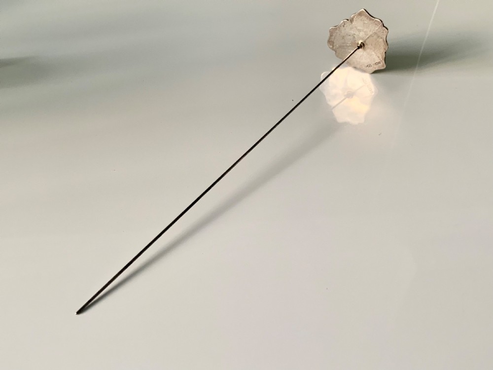 An early twentieth-century silver hatpin crafted in the shape of a pansy flower with iridescent mother-of-pearl top petals and purple enamelled lower petals. View II