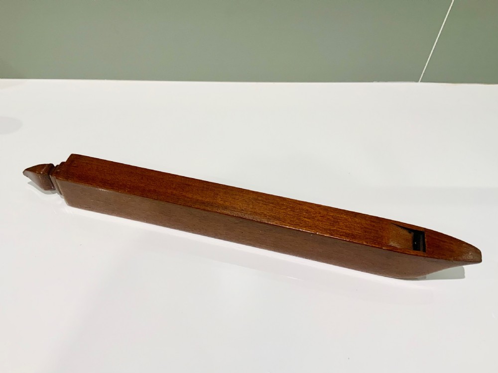 An elongated, rectangular wooden pitch pipe crafted from dark mahogany with a tapered mouthpiece at one end and a sound aperture.