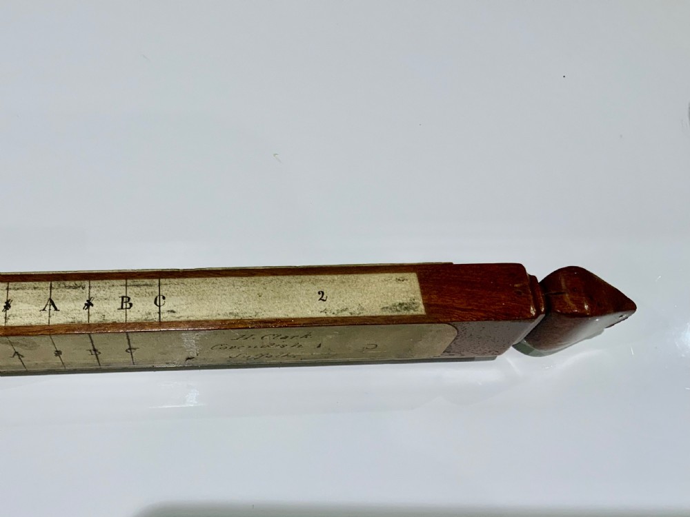 An elongated, rectangular wooden pitch pipe crafted from dark mahogany with a tapered mouthpiece at one end and a sound aperture. View III
