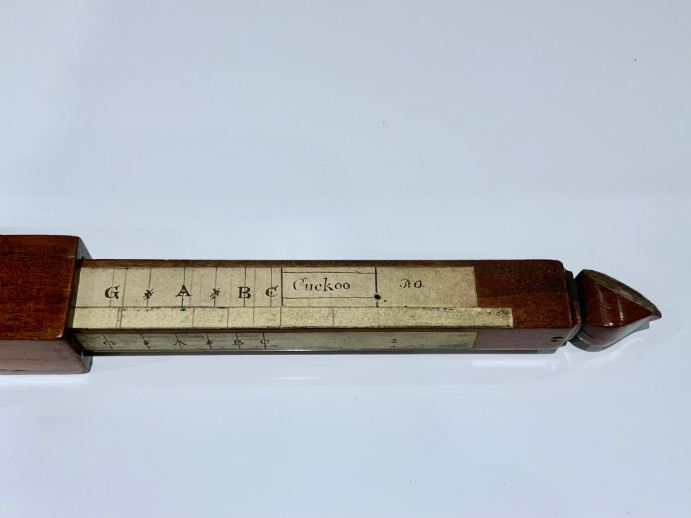 An elongated, rectangular wooden pitch pipe crafted from dark mahogany with a tapered mouthpiece at one end and a sound aperture. View V