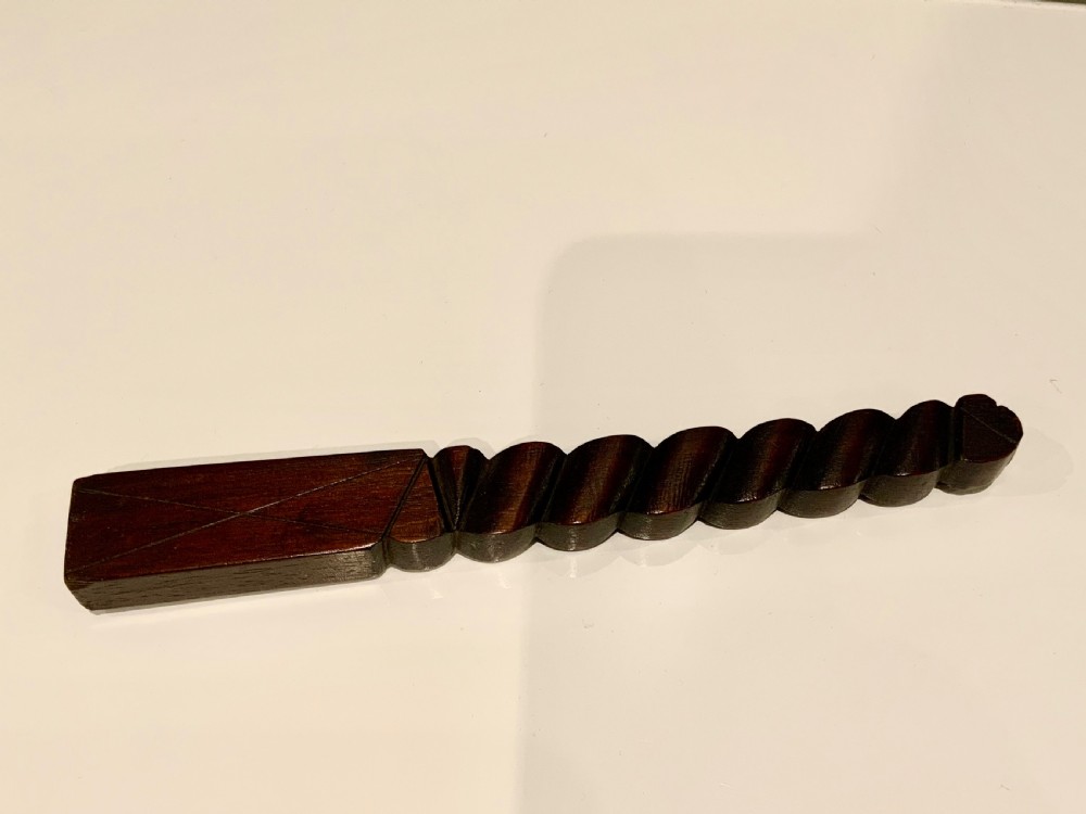 A dark carved wooden 19th-century knitting sheath featuring a heavy spiral-twisted shaft and an inset glass-covered handwritten inscription near the base. View III