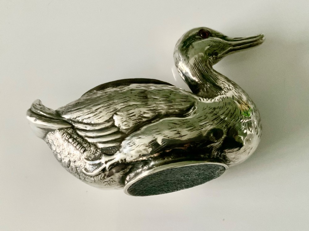 An Edwardian silver novelty pin cushion shaped like a resting duck, featuring detailed feather engraving, red glass eyes, and a dark velvet cushion on its back. View III