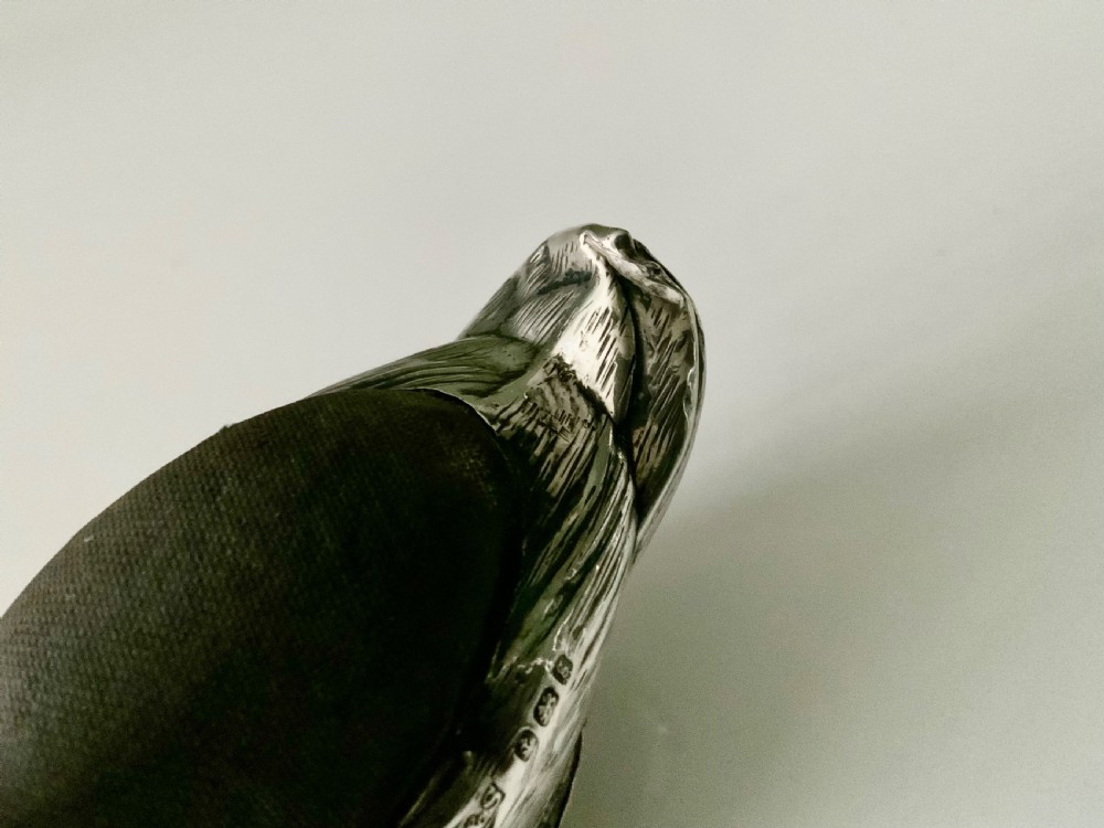 An Edwardian silver novelty pin cushion shaped like a resting duck, featuring detailed feather engraving, red glass eyes, and a dark velvet cushion on its back. View V
