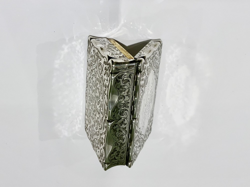 An ornate rectangular silver snuff box with intricate scroll engraving and a central inscription on the hinged lid. View IV