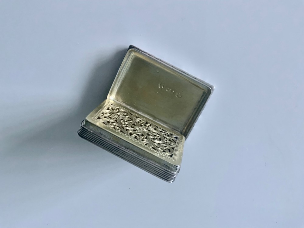 A small rectangular Georgian sterling silver vinaigrette featuring an engraved central cartouche with the inscription Remember Me, framed by basketweave engine turning and a floral cast border. View II