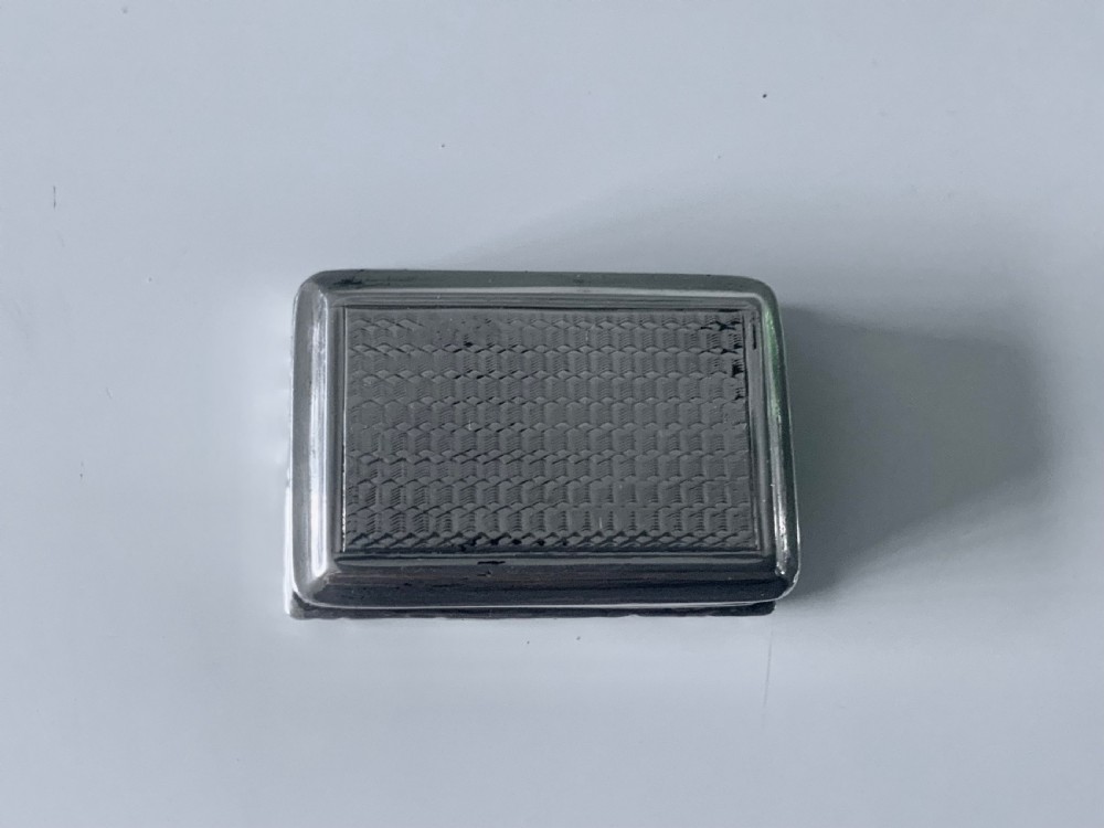 A small rectangular Georgian sterling silver vinaigrette featuring an engraved central cartouche with the inscription Remember Me, framed by basketweave engine turning and a floral cast border. View III