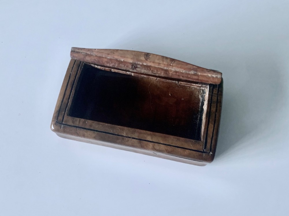 An overhead view of a rectangular antique burr wood snuff box featuring a distinctive swirling wood grain and a small engraved metal plaque set into the lid. View III