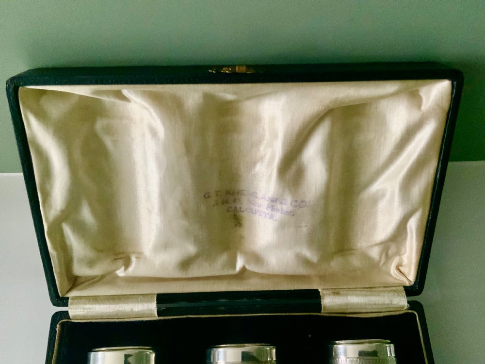 An open black fitted case displaying three cylindrical Art Deco sterling silver canisters with engine-turned decoration and satin lining. View VI