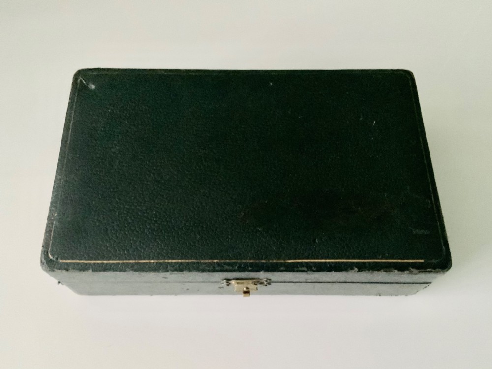 An open black fitted case displaying three cylindrical Art Deco sterling silver canisters with engine-turned decoration and satin lining. View VII