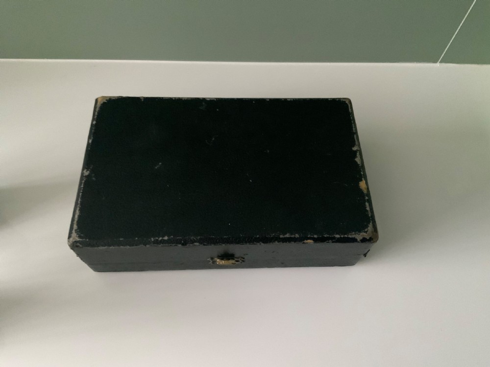 An open black fitted case displaying three cylindrical Art Deco sterling silver canisters with engine-turned decoration and satin lining. View VIII