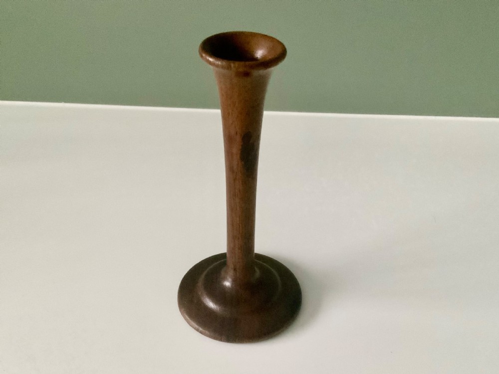A 19th-century turned wooden monaural stethoscope with a slender stem and flared acoustic bell displayed upright.