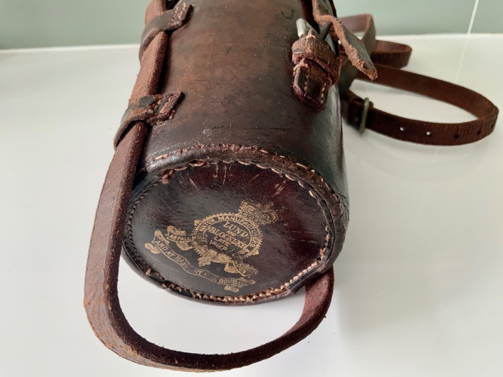 A Victorian silver-plated cylindrical flask engraved with initials alongside a dark brown leather carrying case with a shoulder strap. View II