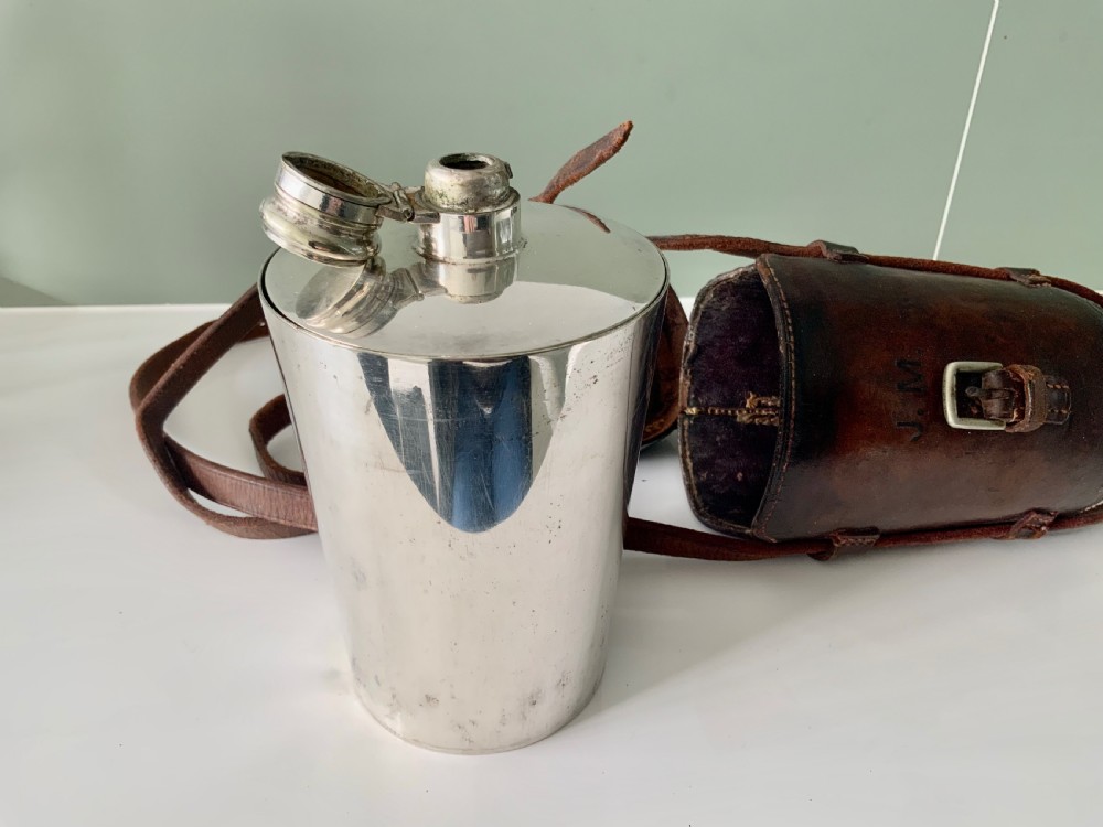 A Victorian silver-plated cylindrical flask engraved with initials alongside a dark brown leather carrying case with a shoulder strap. View IV