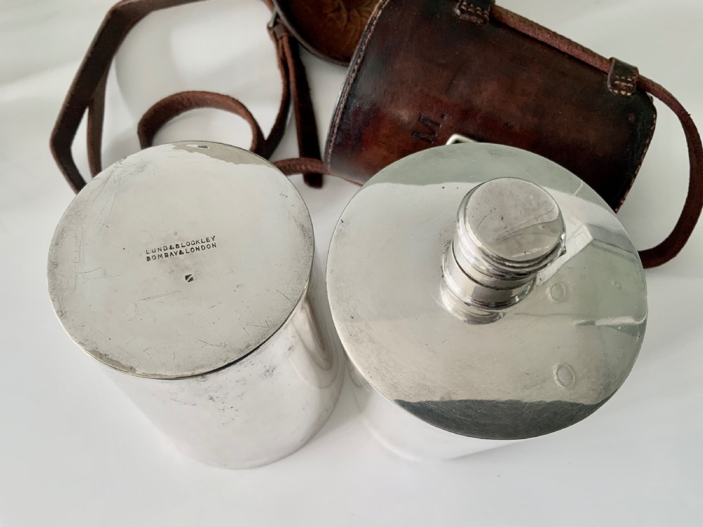 A Victorian silver-plated cylindrical flask engraved with initials alongside a dark brown leather carrying case with a shoulder strap. View V