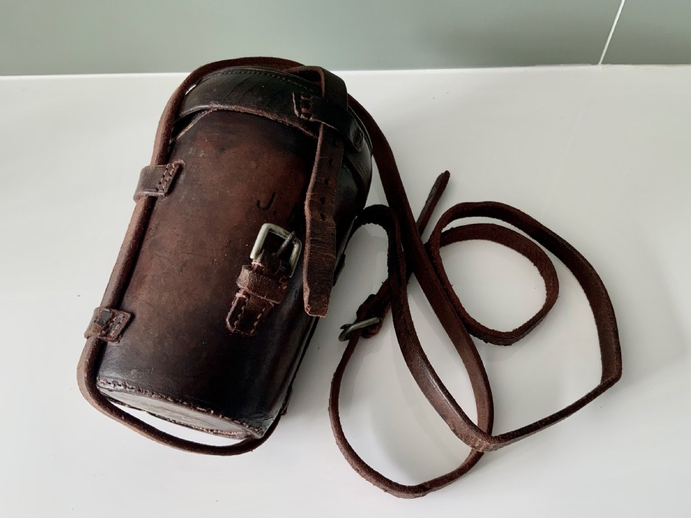 A Victorian silver-plated cylindrical flask engraved with initials alongside a dark brown leather carrying case with a shoulder strap. View VIII